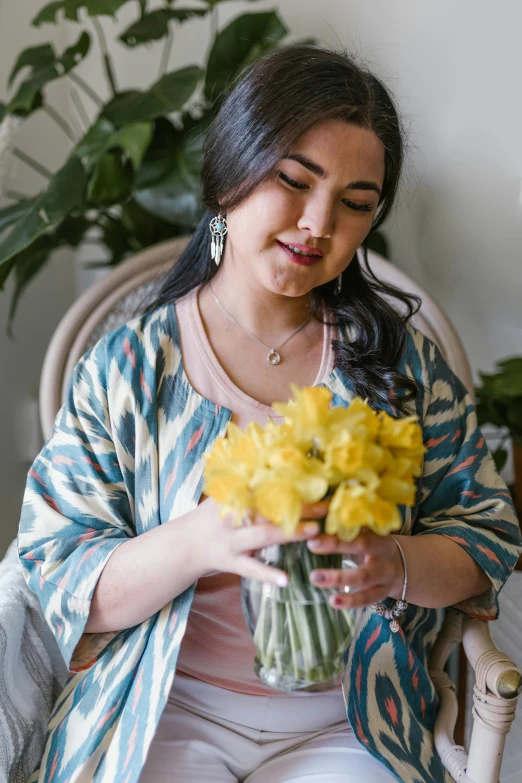 a woman sitting in a chair holding a bouquet of flowers, wearing yellow floral blouse, zenra taliyah, hyacinth blooms surround her, helpful