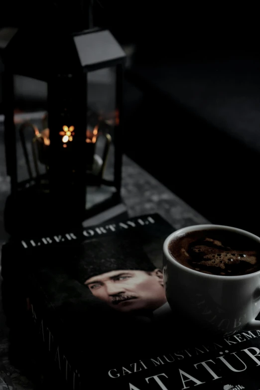 a book sitting on top of a table next to a cup of coffee, an album cover, inspired by irakli nadar, romanticism, cinematic movie image, profile image, dark winter evening, instagram picture