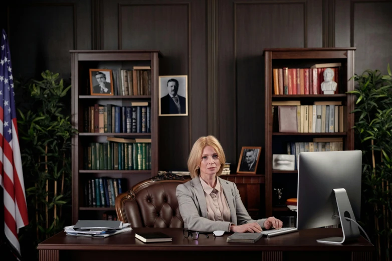 a woman sitting at a desk in front of a computer, by Edi Rama, lawyer clothing, cinematic realistic photo, academician prokhor zakharov, tv show