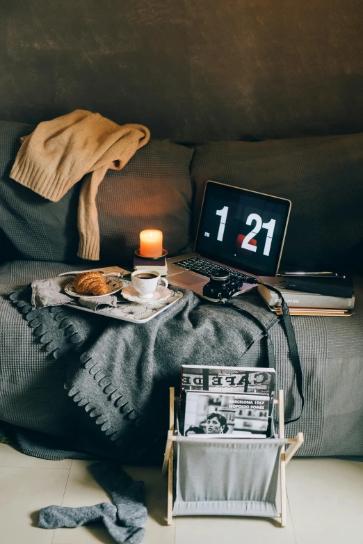 a laptop computer sitting on top of a bed next to a blanket, inspired by Elsa Bleda, pexels contest winner, cozy candlelight, velvet couch, grey, monthly