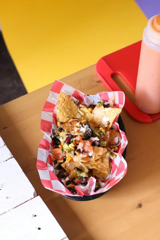 a wooden table topped with a bowl of nachos, graffiti, thumbnail, bingus, pink, vanilla