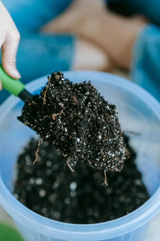 a person scooping dirt into a blue bucket, unsplash, with black vines, close - up on detailed, hdpe, the earth sprouts lava