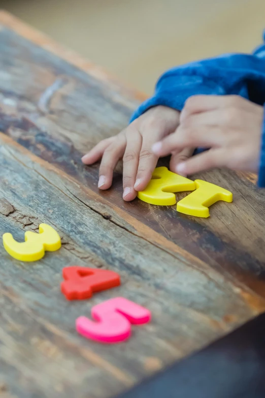 a child playing with wooden letters on a table, by Dan Content, unsplash, multiple stories, yellow, islamic, 15081959 21121991 01012000 4k