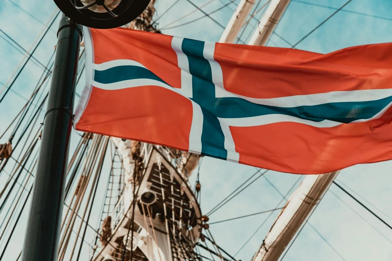 the norwegian flag is flying on the mast of a tall ship, by Jens Søndergaard, pexels contest winner, hurufiyya, white and orange breastplate, 🚿🗝📝, profile image, thumbnail