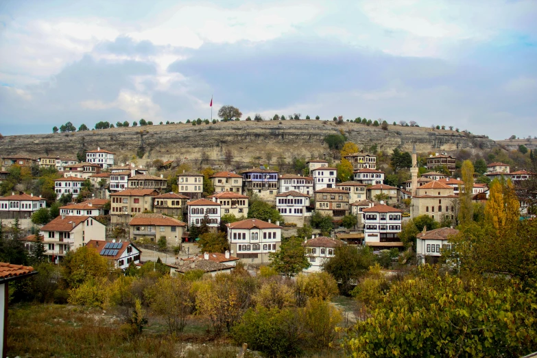 a view of a town with a hill in the background, by Yasar Vurdem, pexels contest winner, square, colored photo, panoramic, ayanamikodon and irakli nadar
