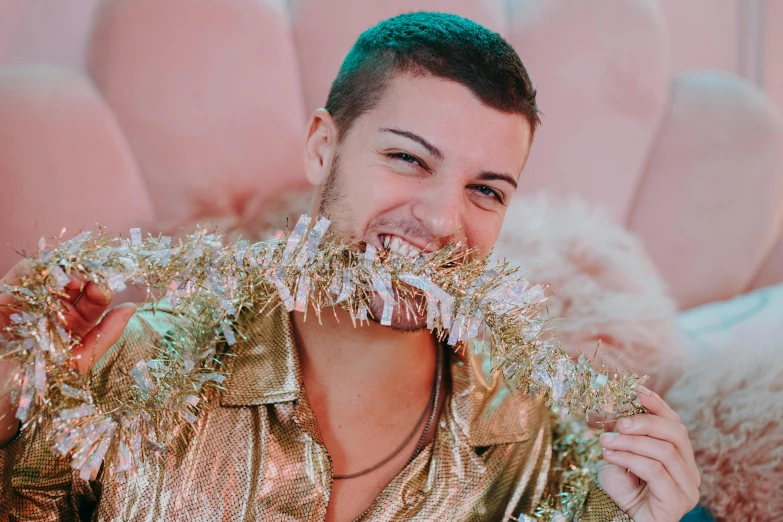 a man sitting on top of a couch covered in tinsel, by Julia Pishtar, trending on pexels, renaissance, shaven stubble, sly smile, charli xcx, gold bra