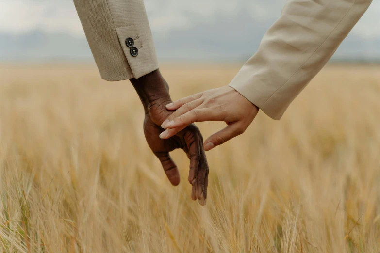 a man and a woman holding hands in a wheat field, a colorized photo, by Carey Morris, trending on pexels, with brown skin, ivory and ebony, elegant hand, thumbnail