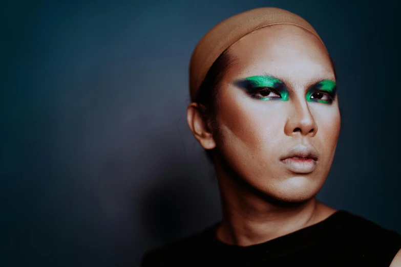 a close up of a person with green makeup, an album cover, inspired by Ina Wong, trending on pexels, male model, malaysian, shaven face, drag