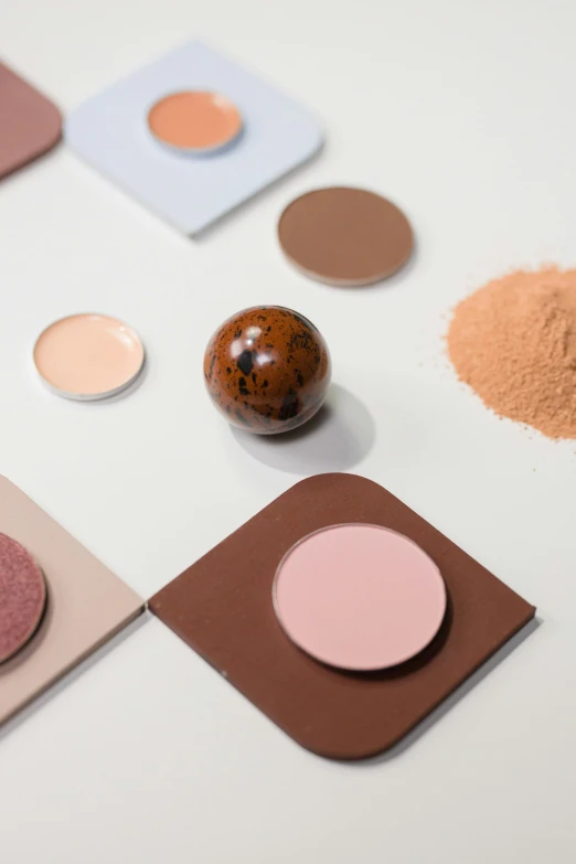 a white table topped with different colored eyeshadows, inspired by Matija Jama, trending on pexels, assemblage, brown, spherical, soft details, products shot