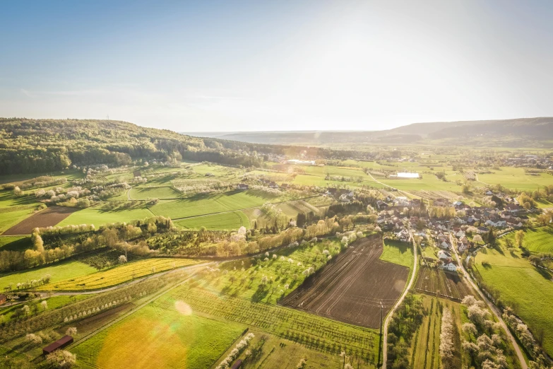 an aerial view of a farm in the countryside, by Matthias Stom, happening, balloon, sunny light, high quality upload, evergreen valley