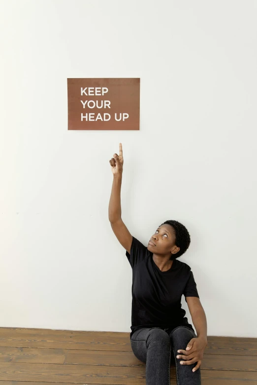 a woman holding a sign that says keep your head up, an album cover, inspired by Kadir Nelson, trending on unsplash, kinetic art, 3 5 mm pointing up, studio shoot, instructions, courtesy of moma