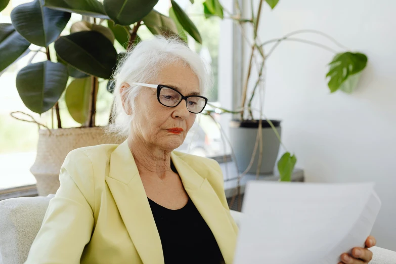 a woman sitting on a couch reading a piece of paper, by Carey Morris, pexels contest winner, white-haired, avatar image, working in an office, al fresco