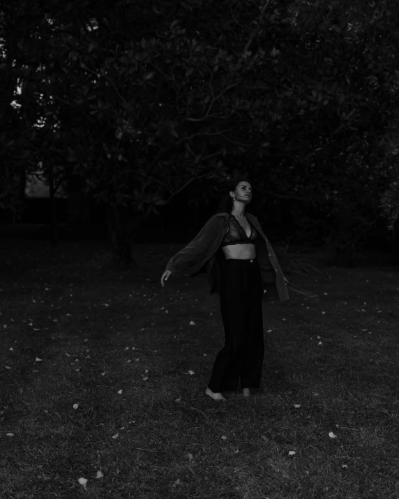 a black and white photo of a woman throwing a frisbee, unsplash, realism, standing in a dark forest, in the yard, ✨🕌🌙, new album cover