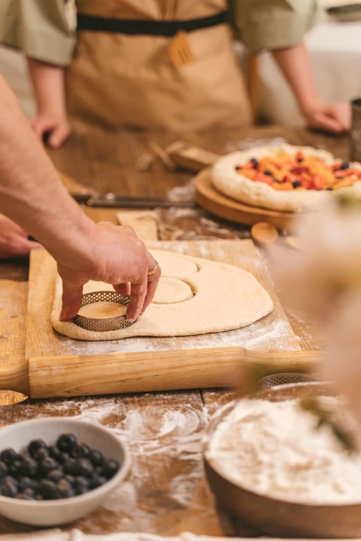 a group of people making pizzas in a kitchen, a marble sculpture, trending on pexels, monogram, a wooden, food art, low detail