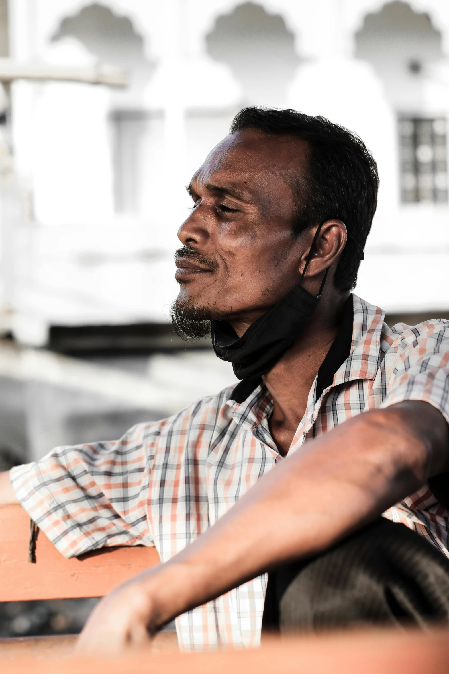 a man sitting on a bench in front of a building, pexels contest winner, renaissance, blind brown man, strong chin, jakarta, profile image