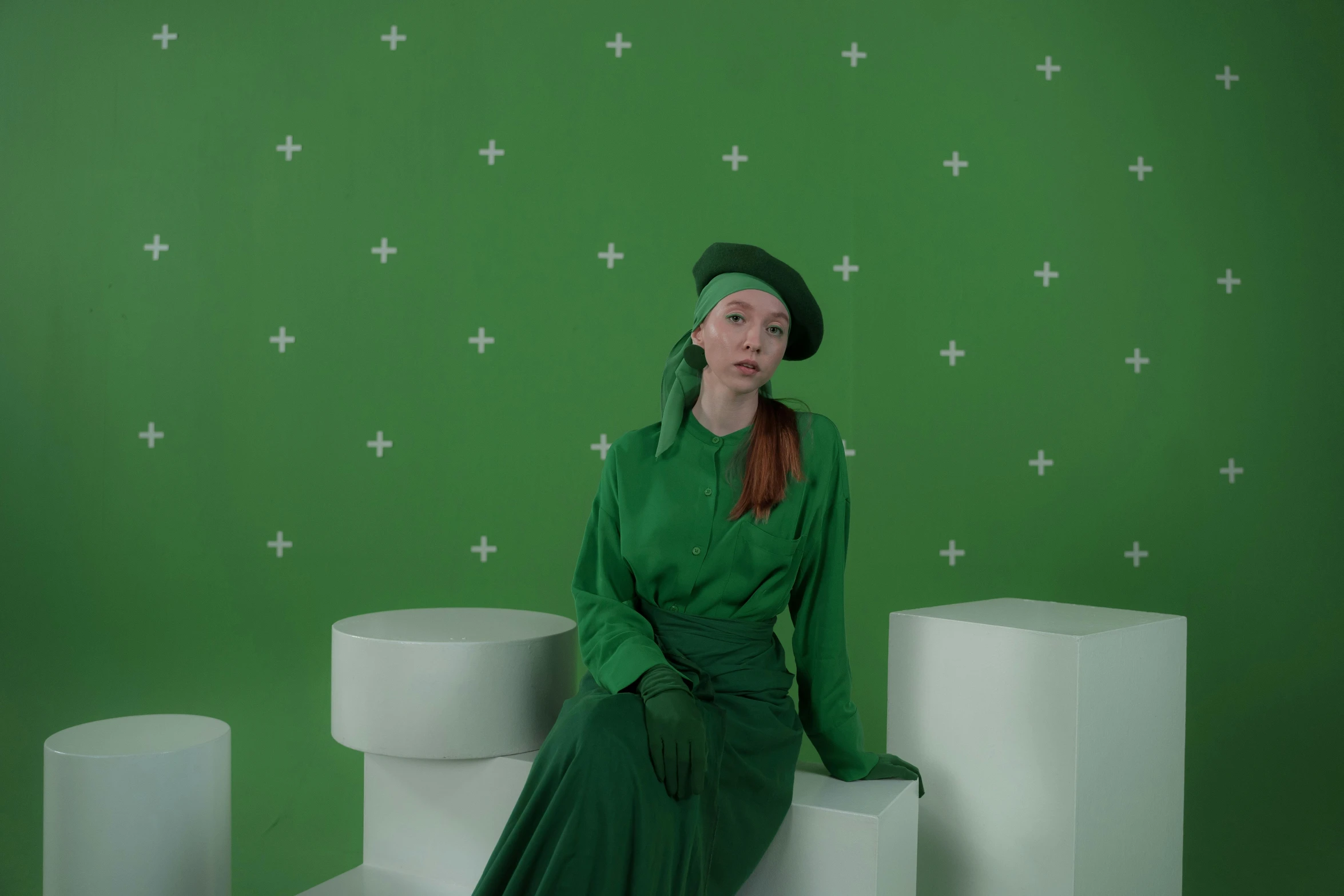 a woman in a green dress sitting on a white pedestal, deviantart, video art, wearing green suit, with hat, sadie sink, green screen