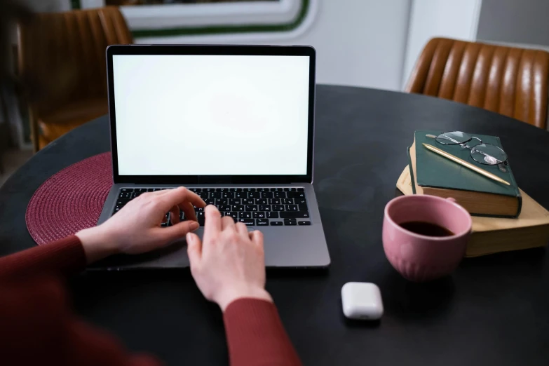 a person sitting at a table with a laptop computer, by Carey Morris, pexels, rectangle, background image, table in front with a cup, online