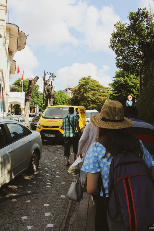 a group of people walking down a street, instagram, bali, yellow school bus, wearing a french beret, portugal