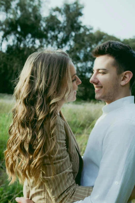 a man and woman standing next to each other in a field, a picture, unsplash, renaissance, turning her head and smiling, lachlan bailey, hair blowing, close - up profile