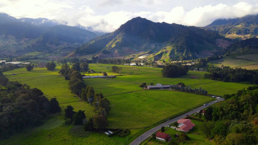 an aerial view of a farm with mountains in the background, sumatraism, avatar image, rosalia vila i tobella, background image, camilo gc