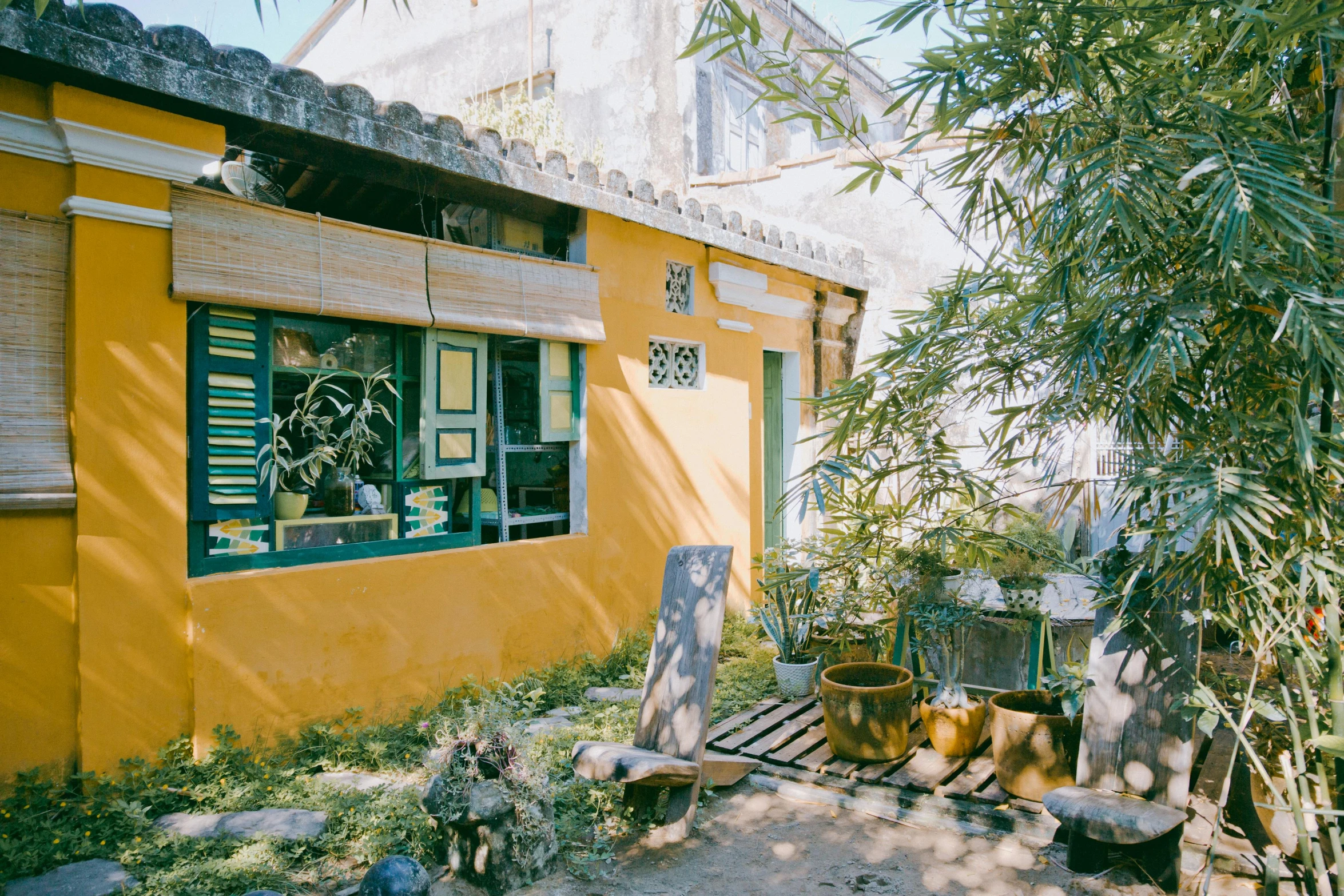 a wooden bench sitting in front of a yellow building, phuoc quan, green house, lime and gold hue, 90s photo