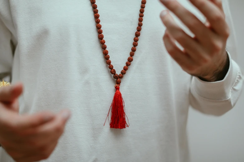 a close up of a person wearing a necklace with a tassel, sukhasana, only red colour, man standing, stressing out