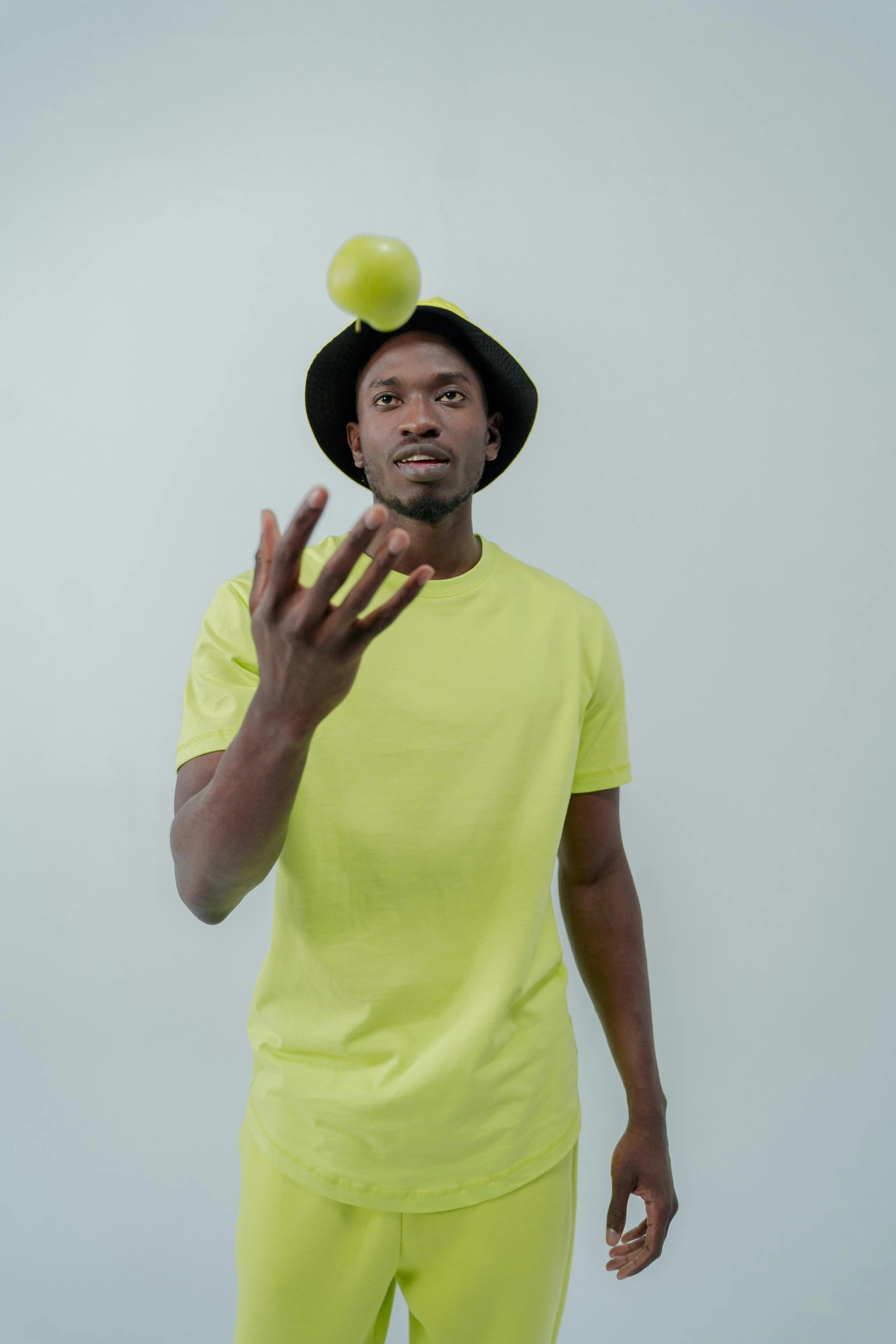 a man with a tennis ball on his head, an album cover, pexels, mkbhd, promo shoot, holding an apple, greeting hand on head