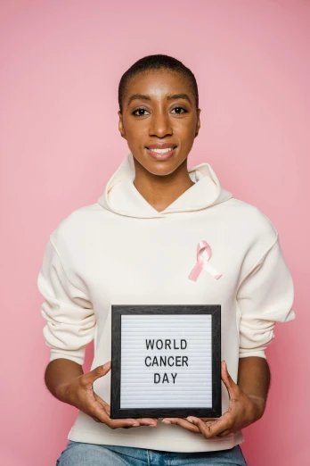 a woman holding a sign that says world cancer day, a photo, by Arabella Rankin, pexels contest winner, ashteroth, a handsome, light pink, maria borges