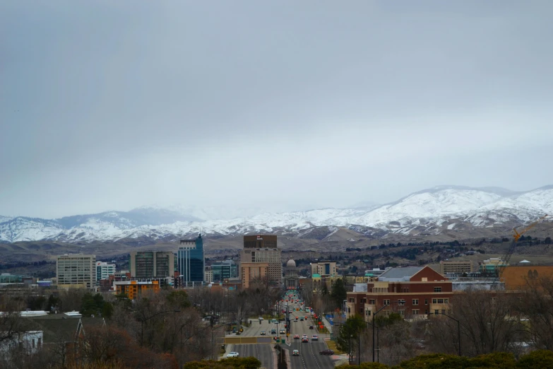 a view of a city with mountains in the background, by Jeffrey Smith, unsplash, snowy mountains, background image, idaho, slide show
