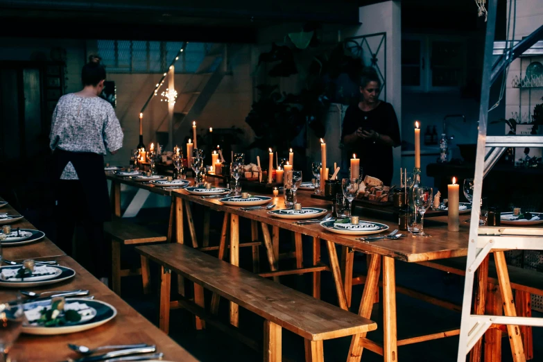 a group of people standing around a long table, by Daniel Lieske, pexels contest winner, hygge, place setting, moody vibe, d. i. y. venue