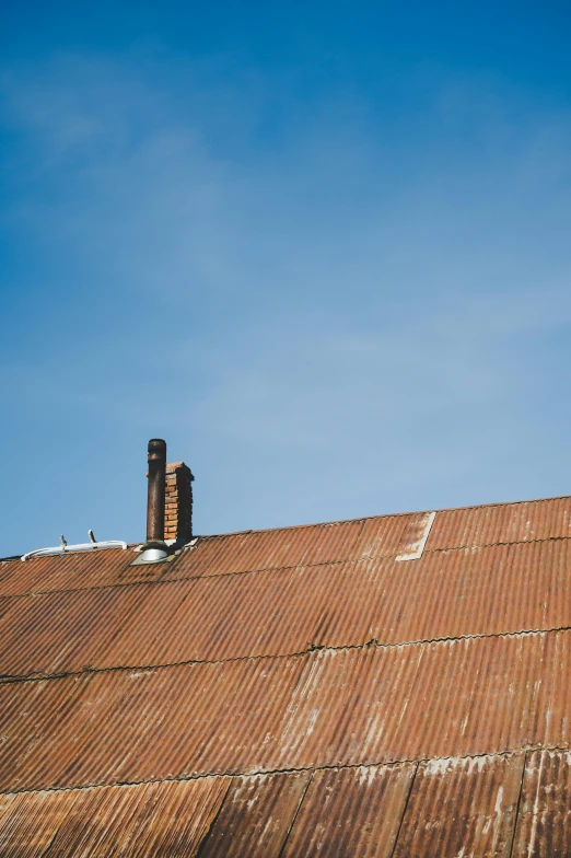 a man riding a snowboard on top of a roof, an album cover, by Andries Stock, unsplash, renaissance, roofing tiles texture, a barn at an iowan farm, smokestacks, cloudless blue sky