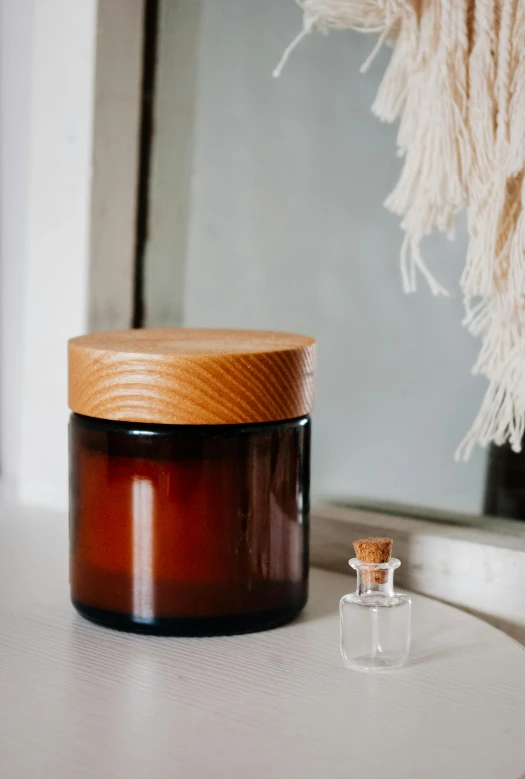 a glass jar with a wooden lid sitting on a window sill, by Nina Hamnett, unsplash, designer product, soap, amber, wooden cabinet