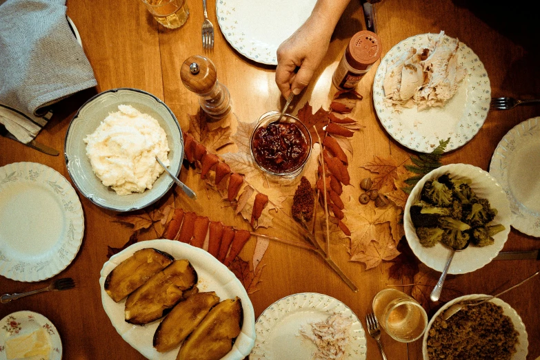 a wooden table topped with plates of food, a photo, by Carey Morris, pexels, leafs, hands pressed together in bow, thumbnail, 8l