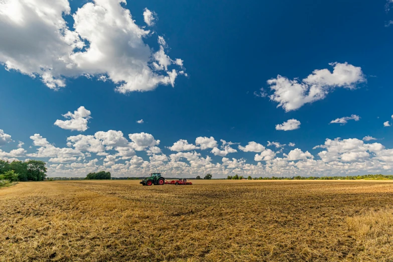 a tractor that is sitting in the middle of a field, a picture, by Andries Stock, panorama view of the sky, ukraine. photography, colour photograph, sunny day time