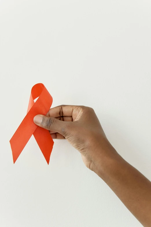 a hand holding a red ribbon against a white background, trending on pexels, medical labels, photo of a black woman, paper cutouts of plain colors, gray men