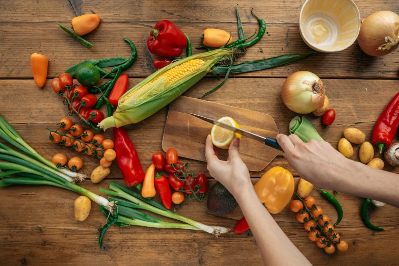 a person cutting vegetables on a cutting board, a still life, by Carey Morris, pexels contest winner, corn, background image, multicoloured, group photo