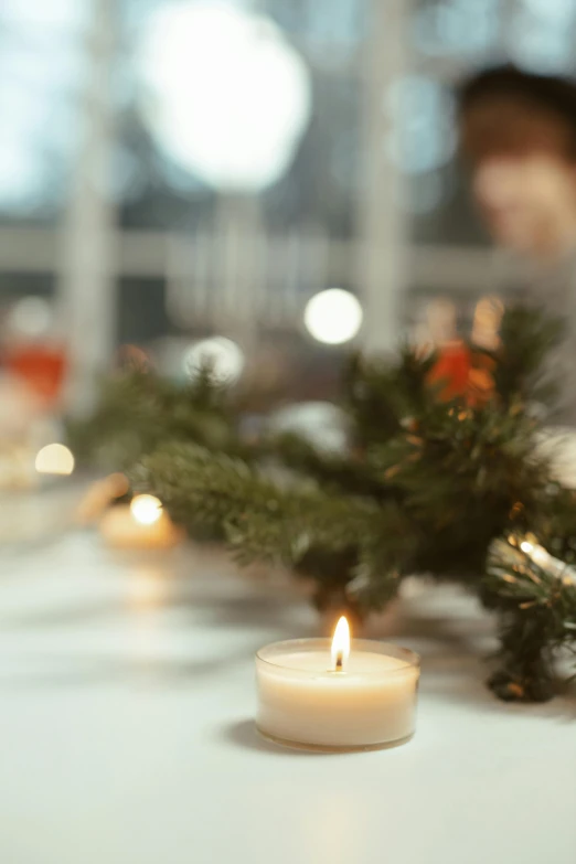 a couple of candles sitting on top of a table, profile image, evergreen branches, person in foreground, long table