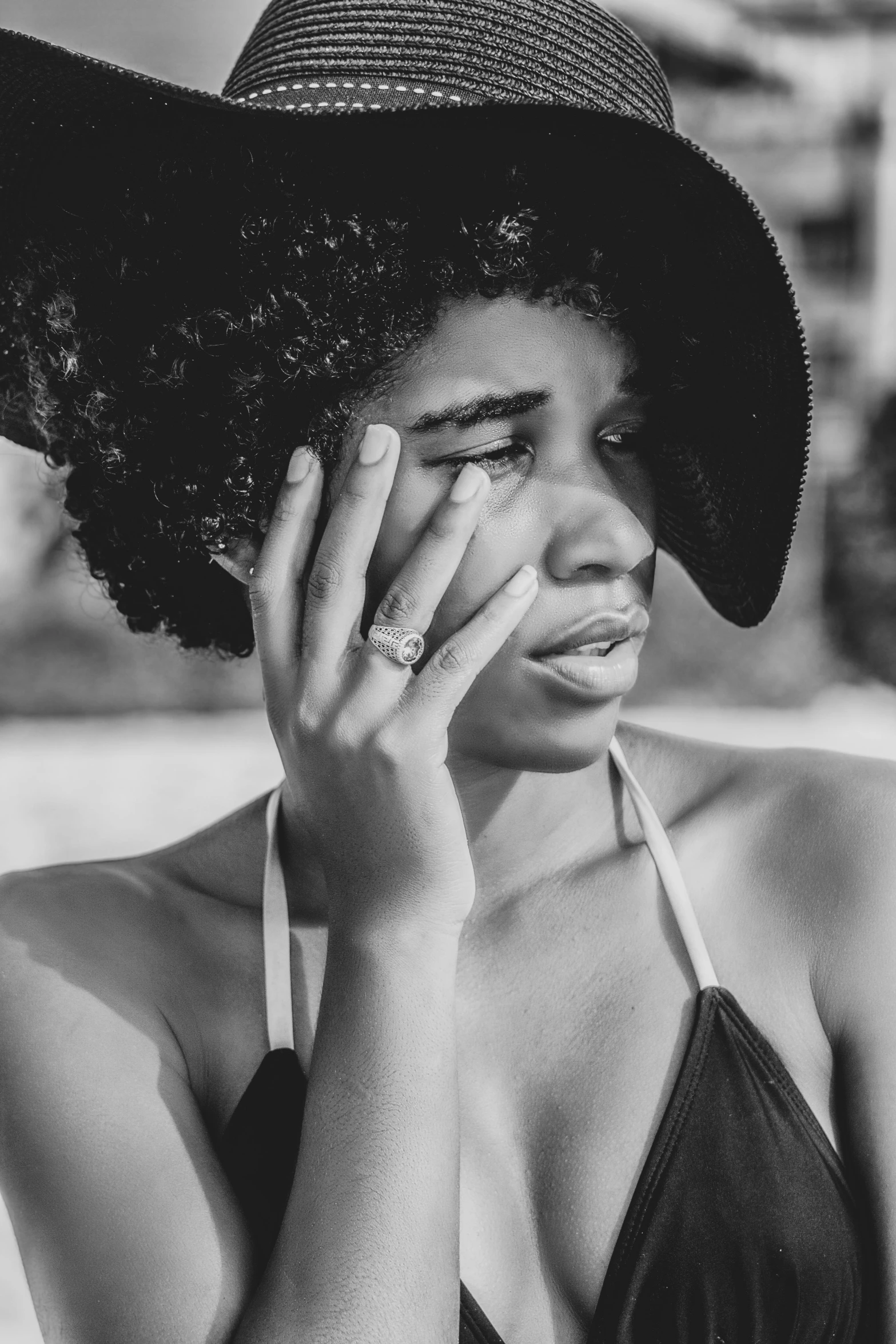 a black and white photo of a woman wearing a hat, by Lily Delissa Joseph, sunburn, hand on cheek, black girl, infp young woman