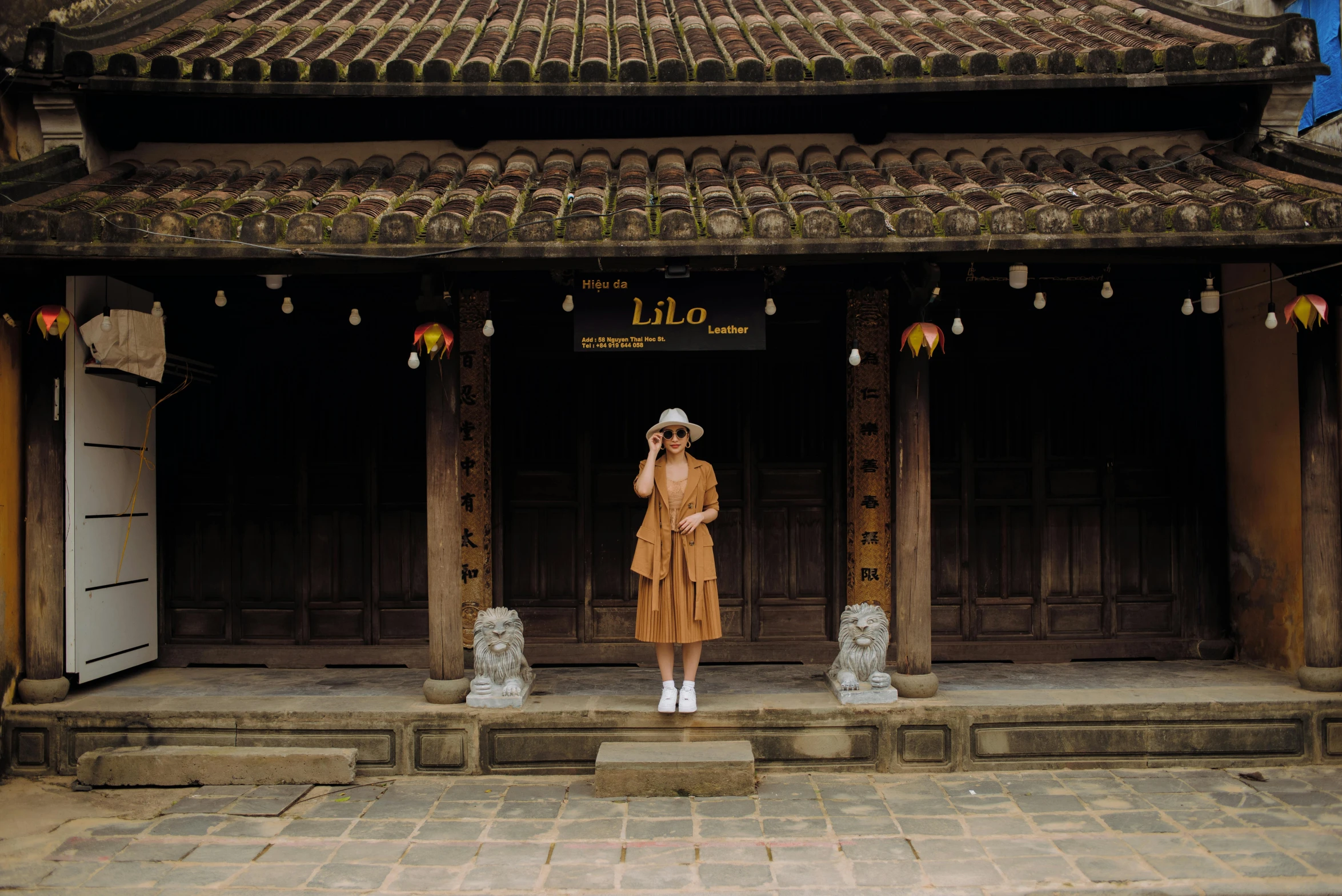 a woman is standing in front of a building, inspired by Lü Ji, unsplash contest winner, brown clothes, in style of lam manh, touhou, 1980s photo