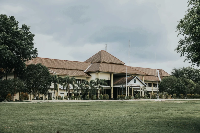 a large building sitting on top of a lush green field, inspired by Erik Pevernagie, unsplash, private school, indonesia, background image, slight overcast lighting