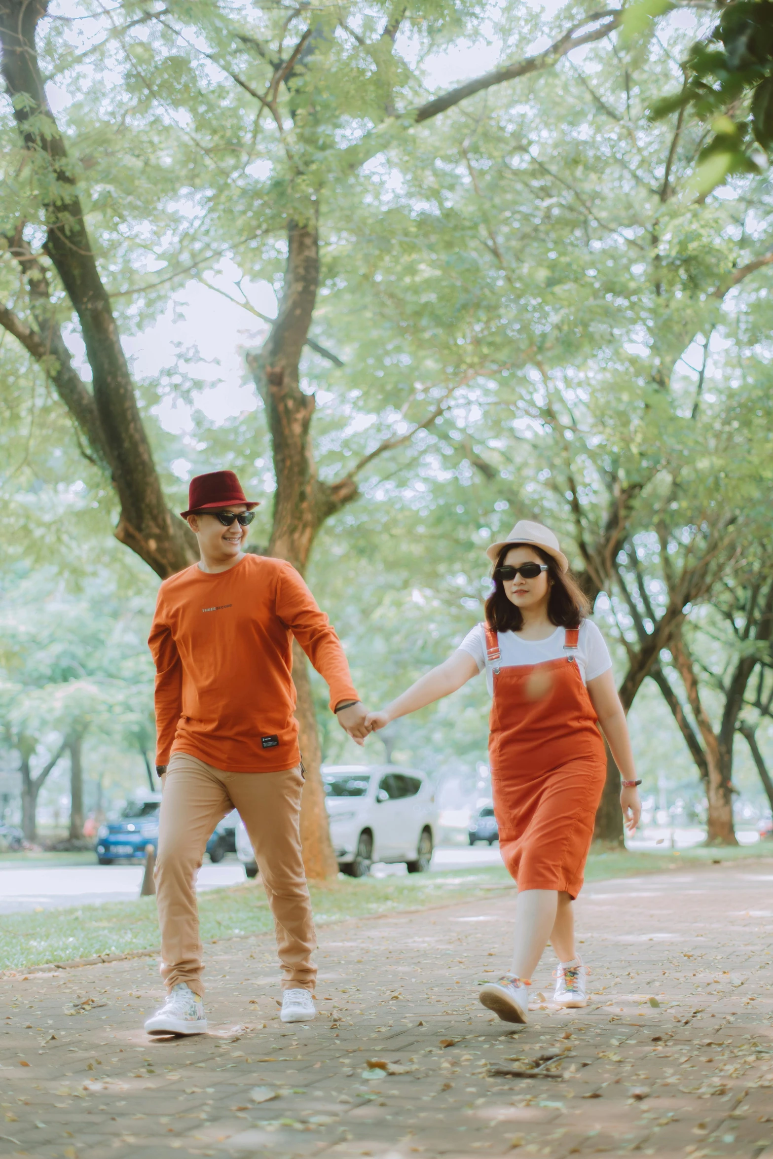 a man and a woman walking down a dirt road, a picture, by Basuki Abdullah, pexels contest winner, wearing orange sunglasses, at a park, casual pose, lawn