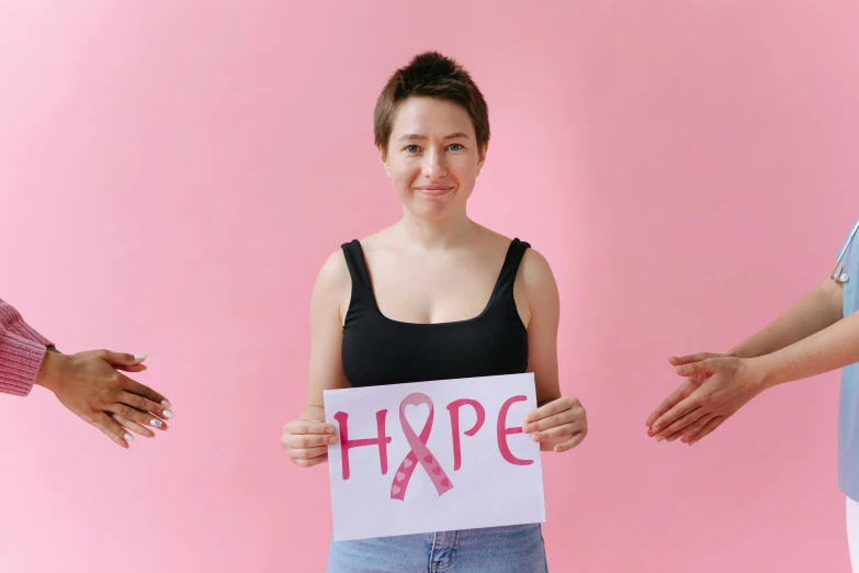 a woman holding a sign that says hope, pexels contest winner, pink body, 3 - piece, disease, young woman in her 20s