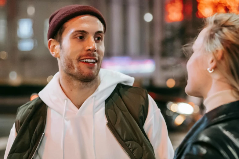 a man standing next to a woman on a street, trending on pexels, happening, wearing a beanie, talking, late night, jay bauman