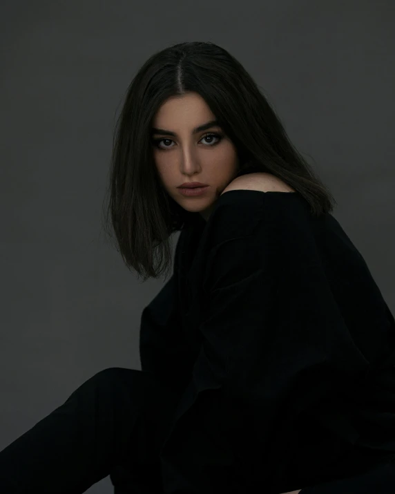 a woman sitting on top of a chair, an album cover, inspired by irakli nadar, pexels contest winner, wearing a black sweater, dark eyes, profile image, middle eastern