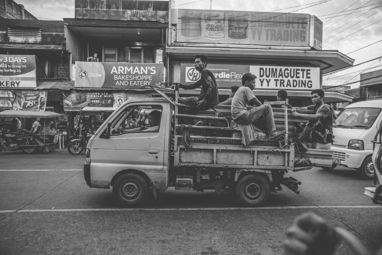 a black and white photo of people riding in the back of a truck, a black and white photo, pexels contest winner, manila, workers, 🕹️ 😎 🔫 🤖 🚬, brown