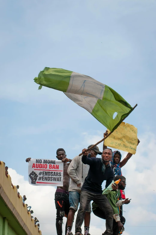 a group of people standing on top of a bridge, an album cover, by Ingrida Kadaka, flickr, happening, protesters holding placards, green flag, emmanuel shiru, in 2 0 1 5