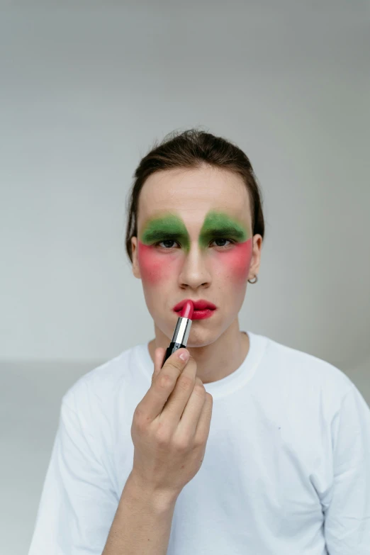 a man is putting makeup on his face, an album cover, inspired by Russell Dongjun Lu, trending on pexels, visual art, green face, transgender, lipstick, julian ope