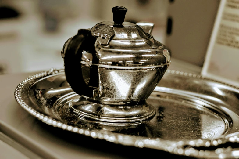 a silver tea pot sitting on top of a silver tray, flickr, diner caffee, black and silver, thumbnail, burned