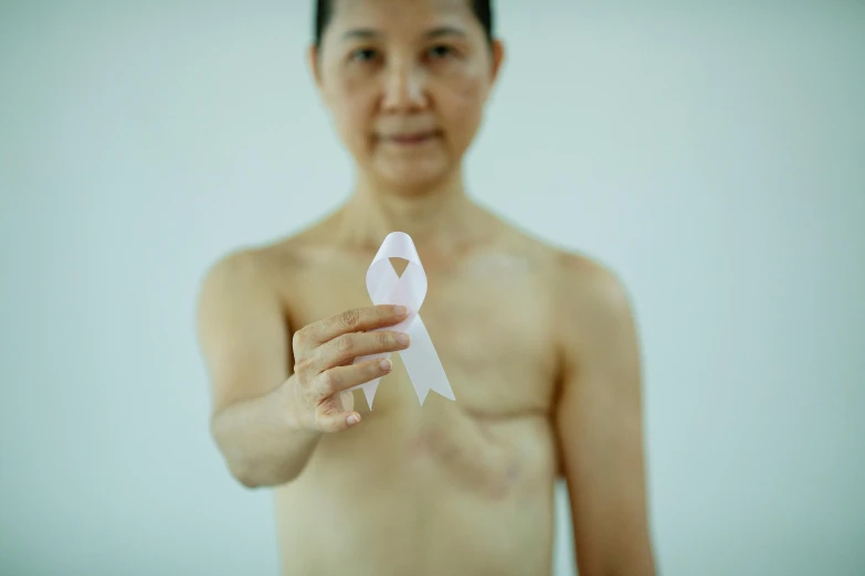 a woman holding a piece of paper with a pink ribbon on it, inspired by Zhang Kechun, pexels contest winner, bandage on arms, mascular, disrobed, split near the left
