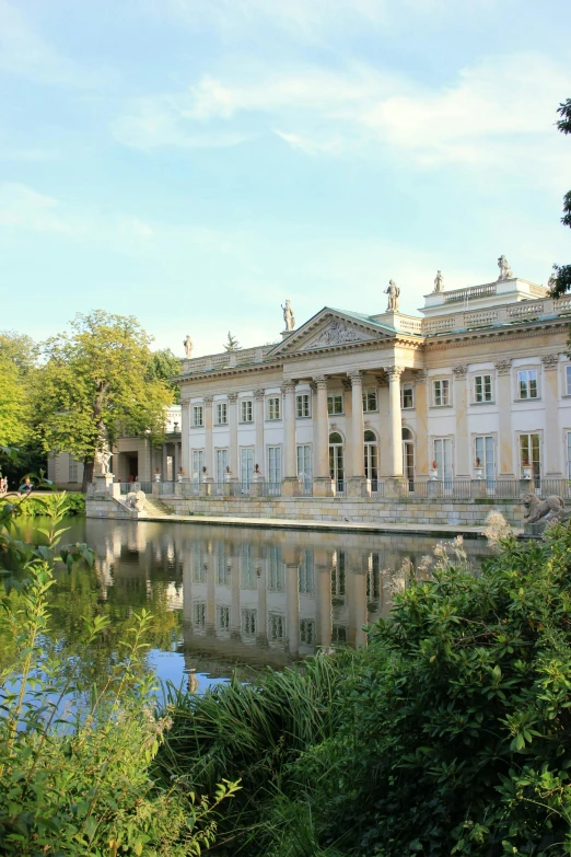 a large building sitting next to a body of water, inspired by Mihály Munkácsy, neoclassicism, warsaw, exterior botanical garden, summertime